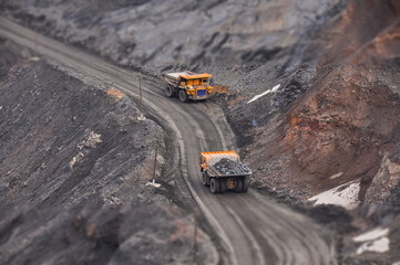 Extraction of iron ore. A mining dump truck transports iron ore along a side carrea. Special equipment works in a quarry © Yevhen