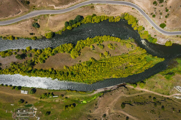 The valley of the Kura River near the cave monastery in Vardzia in Georgia. The bifurcation of the bed of the mountain river view svozdukha. The road along the river bank - obrazy, fototapety, plakaty