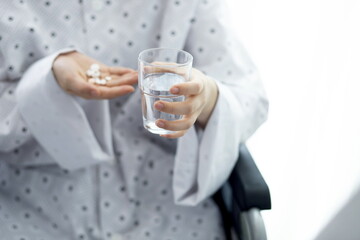 Patient holding pills and glass of water