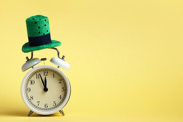 St. Patricks Day celebration concept. Alarm clock in a green hat on a yellow background.