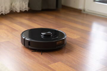 Robot vacuum cleaner on laminate wood floor in living room.