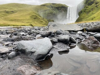 Wasserfall im Hintergrund zu schwarzen Steinen