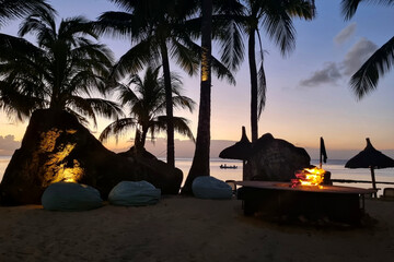 Exotic sunrise on the tropical beach with palms and bonfire 