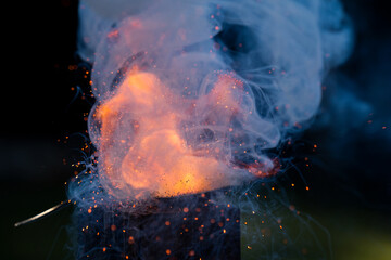Flame explosion of Cracker gunpowder in a spoon with a lot of smoke bubbling and pushing upward