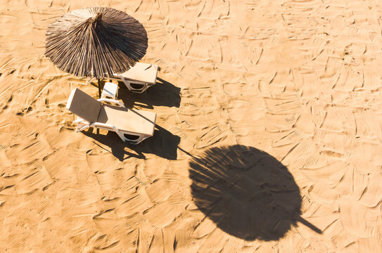 Pair Of Sun Loungers And A Beach Umbrella On A Deserted Beach; Perfect Vacation Concept