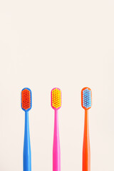 three multi-colored toothbrushes on a beige background. copy space..