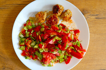 A top view of a fresh brightly teddy salad with patties on a plate.