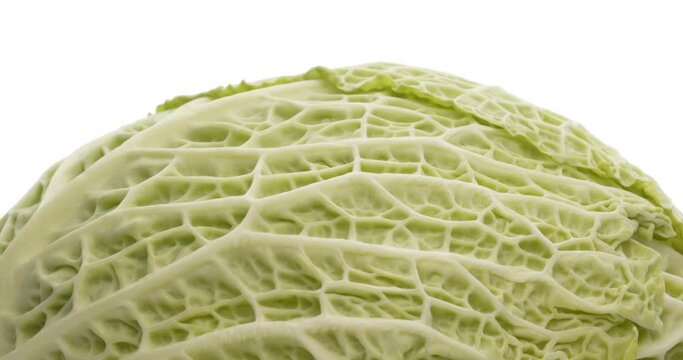 Closeup of savoy cabbage head rotating. Isolated on white background.