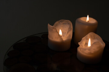 Weihnachtsdekoration. Weiße brennende Kerzen auf einem dekorativen Teller. Dunkler Hintergrund