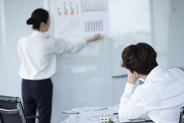 Fototapeta premium Businesswoman Explaining and Pointing at Chart on Board