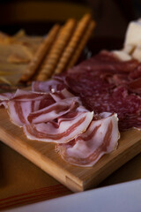 Cheese and meat board in an Italian restaurant in Cremona, Lombardy, Italy with mozzarella, prosciutto, salami, ham, brie, parmesan, bread sticks. Italian food in Europe. European antipasti and snacks