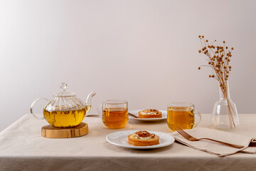 Organic green herbal tea in glass teapot on table. Hot tea is in the glass cups.
