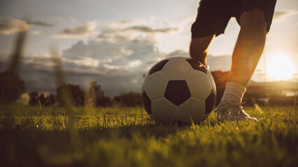 Close up action sport outdoor of football player kicking soccer ball at the field under the...