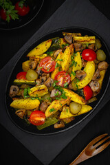 Hot vegetable salad in a plate on a wooden table