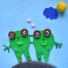 two frogs girlfriends made of fabric and buttons on a blue background