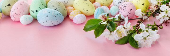 Beautiful Easter card with colorful eggs and cherry branches on paper pink background.