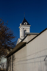 Fototapeta na wymiar The bell tower of the Catholic Church against the blue sky.
