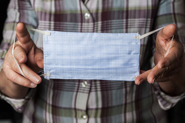 Person holding handmade hand-sewn face mask, shortage of medical protective masks due to global outbreak of COVID-19 corona virus disease, worldwide Coronavirus crisis, do it yourself protection