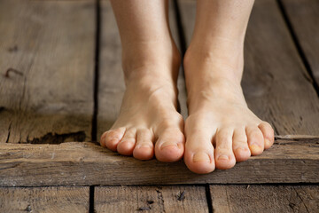 a girl with bare feet walks on an old wooden floor at home