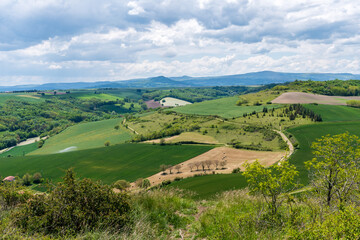 Paysage d'une vallée du puy de dôme verdoyante au printemps avec au fond la chaine des puy 