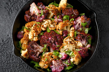 Roasted purple, white cauliflower with herbs on cast iron pan