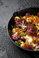Roasted purple, white cauliflower with herbs on cast iron pan