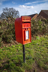 Fototapeta na wymiar Coltishall, Norfolk, UK – February 2022. Free standing red Royal Mail letter box in a small Norfolk village