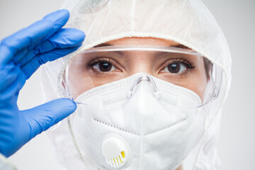 Female lab scientist doctor or nurse putting on protective eyewear goggles