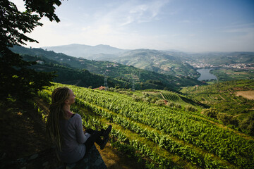 A young woman looks out over the Douro Valley from the hill, Porto, Portugal. - obrazy, fototapety, plakaty