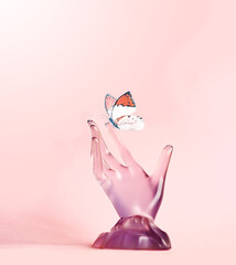 Hand holding a butterfly against a pink background.