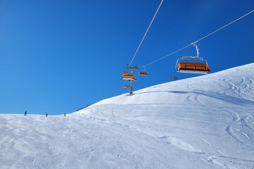Fototapeta na wymiar Ski lift in a ski resort in the german alps. Skiers on a ski slope on a sunny winter day.
