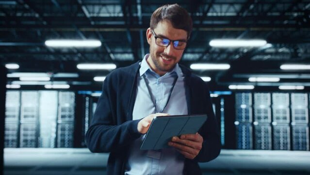 Male IT Specialist Walks Between Row of Operational Server Racks in Data Center. Engineer Uses Tablet Computer for Maintenance and Diagnostics in Cyber Security and Data Protection Facility.