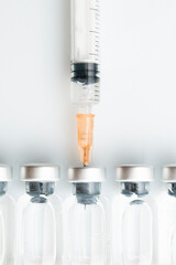 Conceptual background for vaccination campaign: a syringe draws liquid from a vial placed in a row with other vials