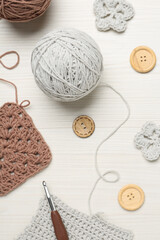 Flat lay composition with knitting threads and crochet hook on white wooden table