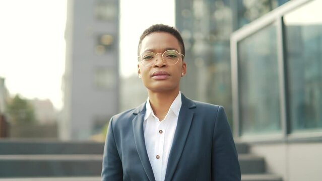 portrait confident serious african american business woman standing on urban office center looking at camera. outdoor. Independent female teacher or associate professor with glasses outside, Close up