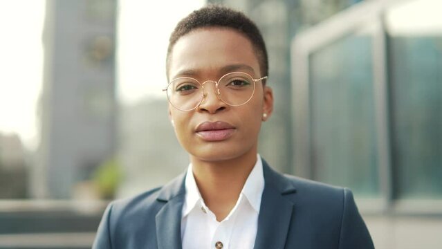 portrait confident serious african american business woman standing on urban office center looking at camera. outdoor. Independent female teacher or associate professor with glasses outside, Close up