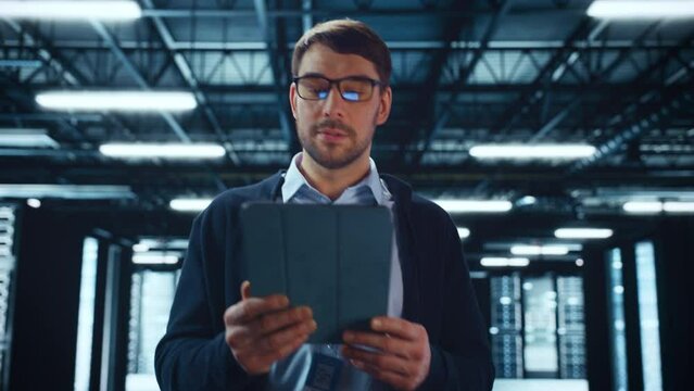 Successful Data Center IT Specialist Using Tablet Computer. Server Farm Cloud Computing Facility with System Administrator Working. Data Protection Engineering Network for Cyber Security.