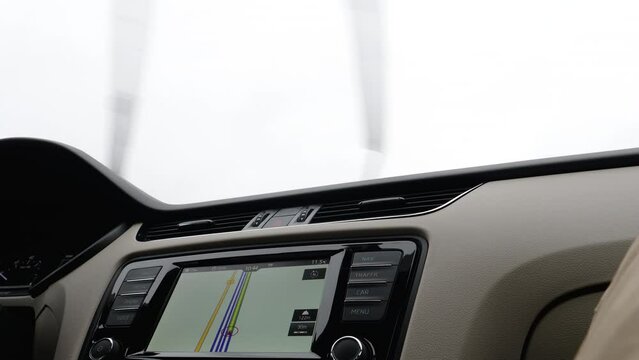 Driving car with GPS generic map on the dashboard display rainy weather wipers working - new luxury electric car
