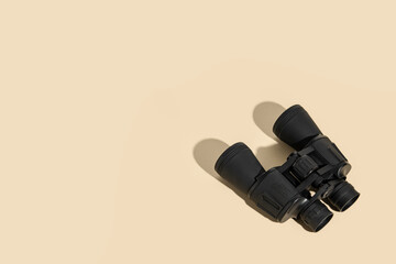 Binoculars black on a beige background. Top view, flat lay.