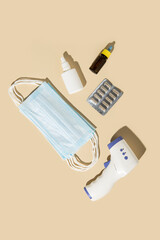 Medical face masks, capsules, nasal spray on a beige background. Top view, flat lay.