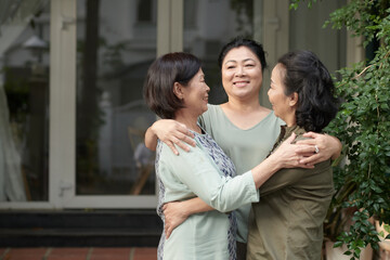 Cheerful senior women happy to see each other after lockdown, they are hugging in front of house