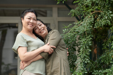 Happy senior female best friends hugging to express positive emotions
