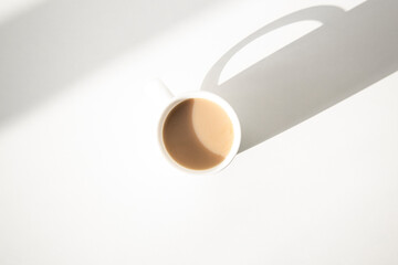 White cup under natural light on a white background. Top view flat lay.