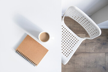 White cup of coffee, a notebook on a white table, there is a chair next to it. Top view, flat lay.