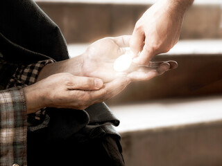 Close up hand giving coin to homeless people or beggar