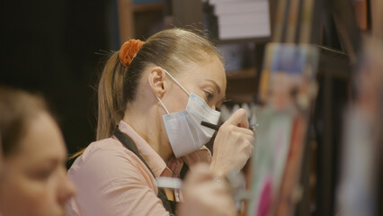 Woman artist learns to paint with airbrush with acrylic dye, paper and easel. Indoors. Concept...