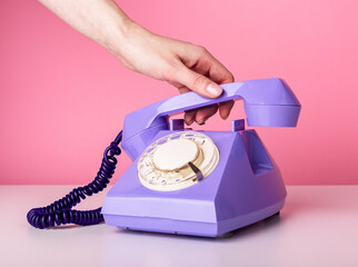 Hand holding retro phone handset, receiver closeup on pink background. Vintage style. High quality photo
