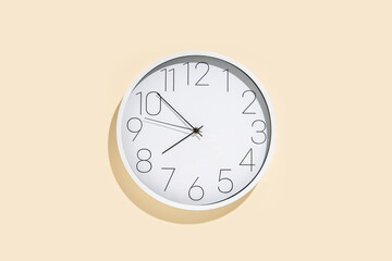 Large white wall clock on a beige wall. Clock showing the time.