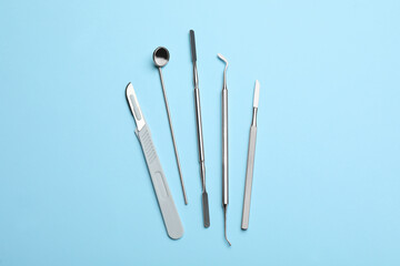 Set of different dentist's tools on light blue background, flat lay