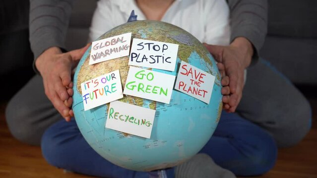 Family hands, son and father,  hug Earth globe with stickers with the message Save the Planet, Help and No Plastic, Recycling, SOS. Concept save our planet and climate change due  global warming 